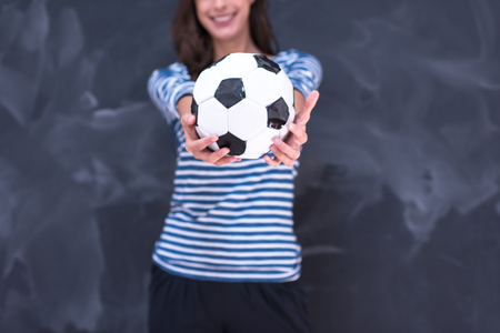portrait of a young woman holding a soccer ball in front of chalk drawing boardの写真素材