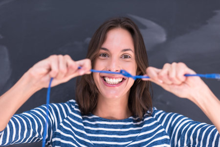 portrait of a young woman holding a internet cable in front of chalk drawing board
