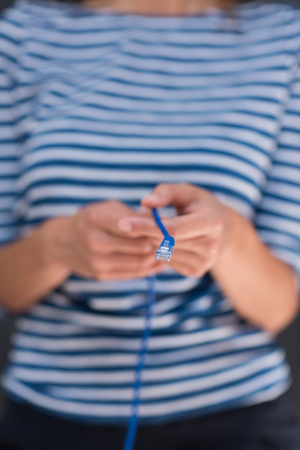 portrait of a young woman holding a internet cable in front of chalk drawing boardの写真素材