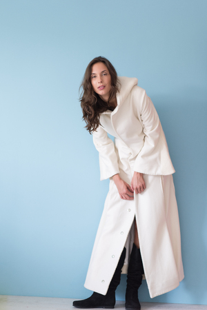 portrait of Beautiful young woman wearing a white coat with hood isolated on blue backgroundの写真素材