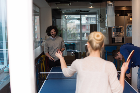 group of young startup business people playing ping pong tennis at modern creative officeの写真素材