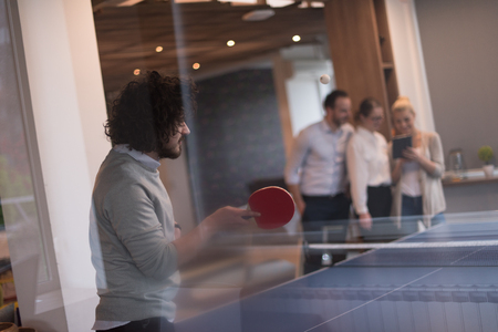 group of young startup business people playing ping pong tennis at modern creative officeの写真素材