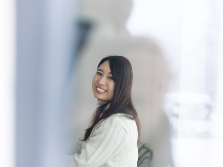 young beautiful asian woman sitting near window at cold winter dayの写真素材