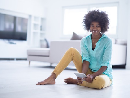 beautiful young black women using tablet computer on the floor at homeの写真素材
