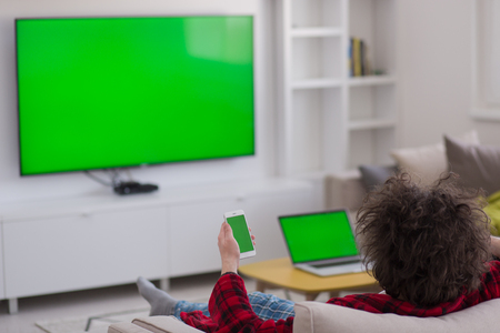 young handsome man in bathrobe enjoying free time watching television in his luxury homeの写真素材