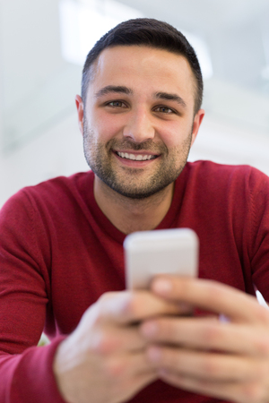 Handsome casual young man using a mobile phone at  homeの写真素材