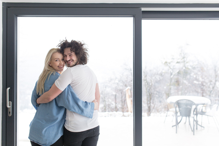 romantic happy young couple enjoying morning coffee by the window on cold winter day at homeの写真素材
