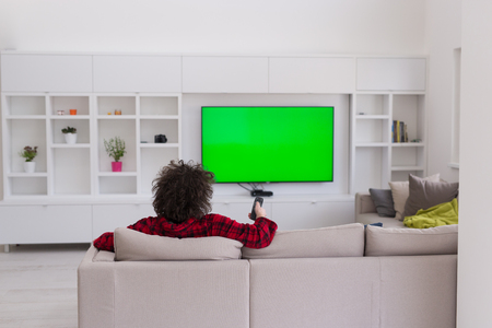 young handsome man in bathrobe enjoying free time watching television in his luxury homeの写真素材