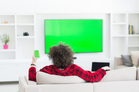 young handsome man in bathrobe enjoying free time watching television in his luxury homeの写真素材