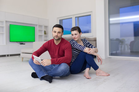 Young Couple sitting on the floor and using interent on digital tabletの写真素材