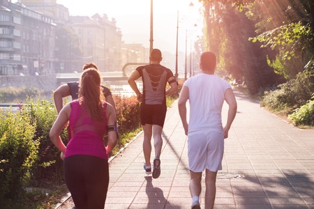 group of young sporty people jogging at sunny morning in the cityの写真素材