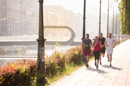 group of young sporty people jogging at sunny morning in the cityの写真素材