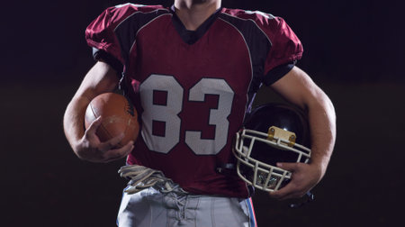 portrait of young confident American football player on field at night
