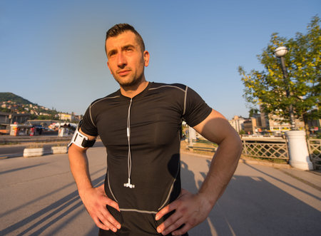 portrait of a young sporty jogging man at sunny morning in the city