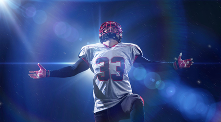 american football player celebrating after scoring a touchdown on the field of big modern stadium with lights and flares at nightの写真素材