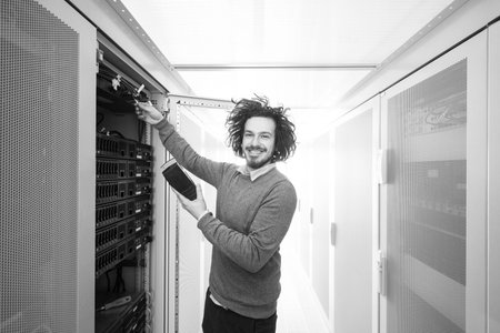 young IT technician using digital cable analyzer on server in large data centerの写真素材