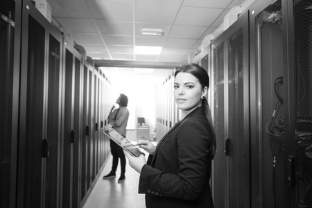 Female IT engineer working on a tablet computer in server room at modern data center