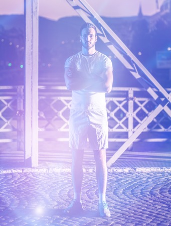 urban sports, young healthy man jogging across the bridge in the city at early morning in nightの写真素材