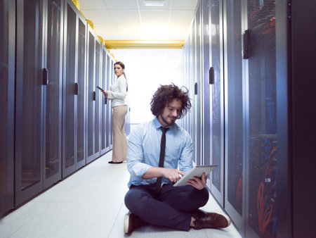 Team of young technicians working together on servers at the data center using tablet computers