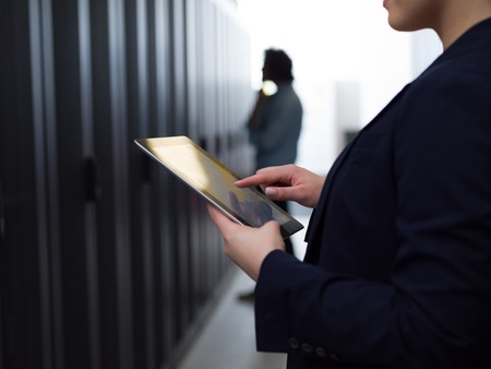 Female IT engineer working on a tablet computer in server room at modern data centerの写真素材