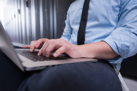 Male IT engineer working on a laptop in server room at modern data centerの写真素材