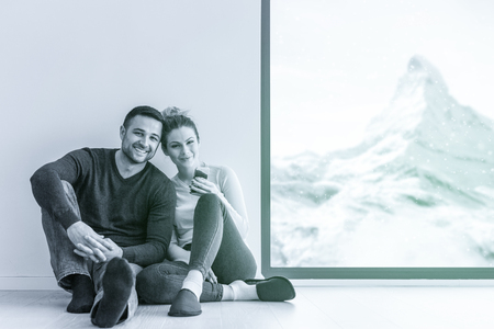 happy young couple sitting near window at home on cold winter dayの写真素材