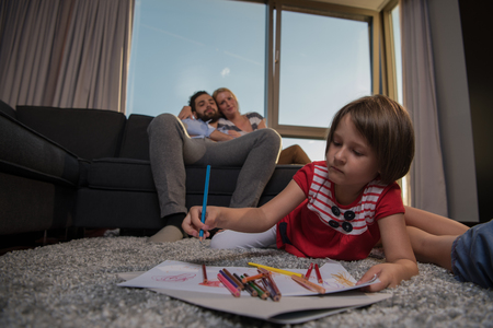 Happy Young Family Playing Together at home on the floor using a tablet and a children's drawing setの写真素材