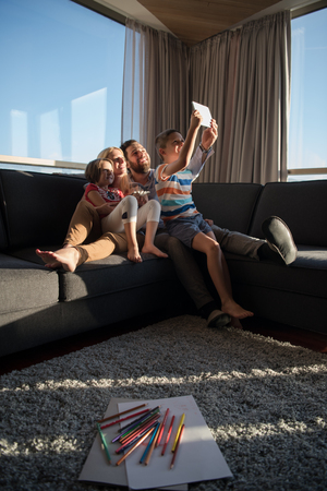 happy couple spending time with kids using tablet computer on sofa at homeの写真素材
