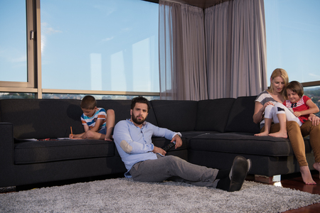 Happy Young Family Playing Together on sofa at home using a tablet and a children's drawing setの写真素材
