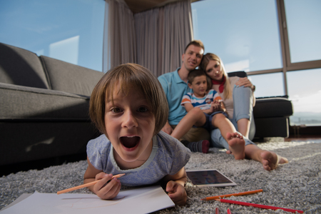 Happy Young Family Playing Together at home on the floor using a tablet and a children's drawing setの写真素材