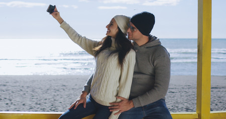 Very Happy Couple In Love Taking Selfie On The Beach in autmun dayの写真素材
