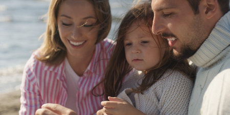 Family with kids resting and having fun at beach during autumn day