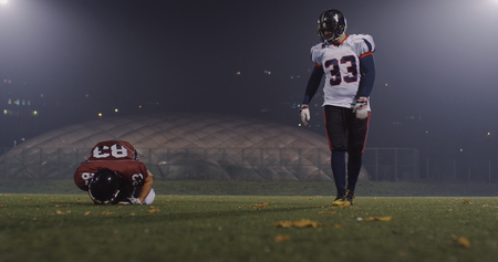 American football players in action at night game time on the fieldの写真素材