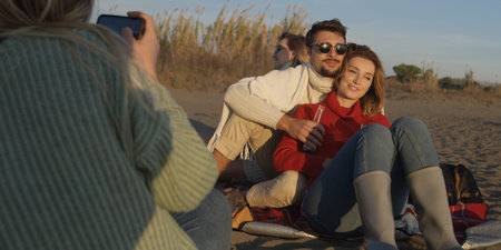 Young Couple Relaxing By The Fire, Drinking A Beer Or A Drink From The Bottle.の写真素材