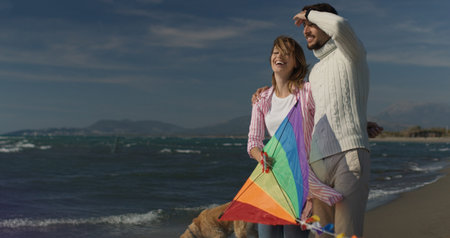 Loving Couple Flying A Kite at Beach and having fun on autumn dayの写真素材