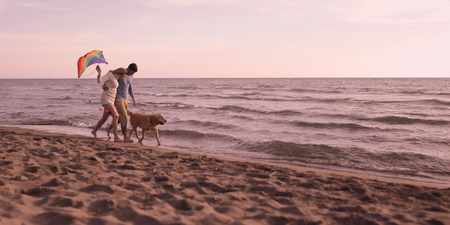 Couple Running On The Beach Holding Their Hands with dog On autmun dayの写真素材