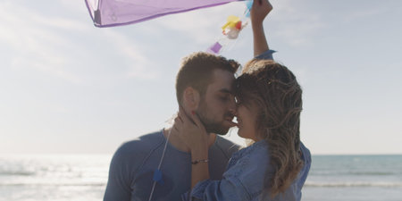 Loving Couple Flying A Kite at Beach and having fun on autumn dayの写真素材