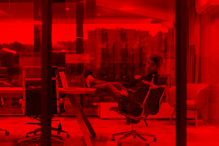 A time for relax. Young tired casual businessman relaxing at the desk in his officeの写真素材