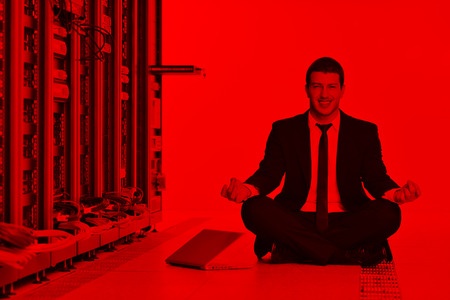 young handsome business man in black suit and tie practice yoga and relax at network server room while representing stres control conceptの写真素材