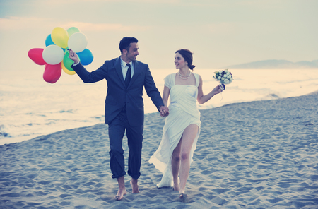 happy just married young couple celebrating and have fun at beautiful beach sunsetの写真素材