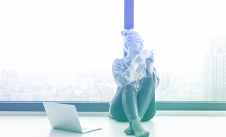 Real Woman Using laptop on the floor Drinking Coffee Enjoying Relaxing at cold winter dayの写真素材