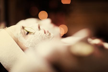portrait of beautiful woman with cosmetic mask on face in spa and  wellness salonの写真素材