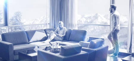 Young couple relaxing at  home using tablet computer reading in the living room near the window on the sofa couch.の写真素材