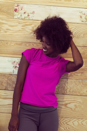portrait of cute african american woman with afro hairstyle while  posing against old retro wooden backgroundの写真素材