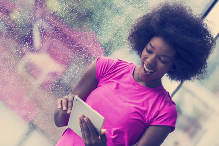 beautiful african american woman using tablet computer from home while rain and bad weather is outdoorの写真素材