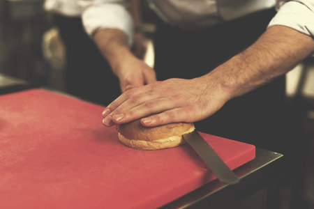 master chef hands cutting rolls for a burger in the rastaurant kitchen