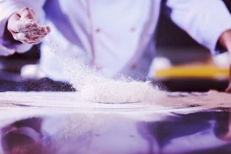 chef hands preparing dough for pizza on table sprinkled with flour closeup