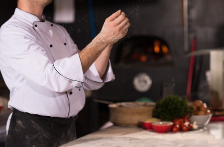 Skilled chef preparing dough for pizza rolling with hands and throwing upの写真素材
