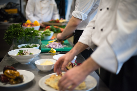 Professional team cooks and chefs preparing meal at busy hotel or restaurant  kitchenの写真素材