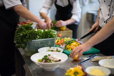 Professional team cooks and chefs preparing meals at busy hotel or restaurant  kitchenの写真素材
